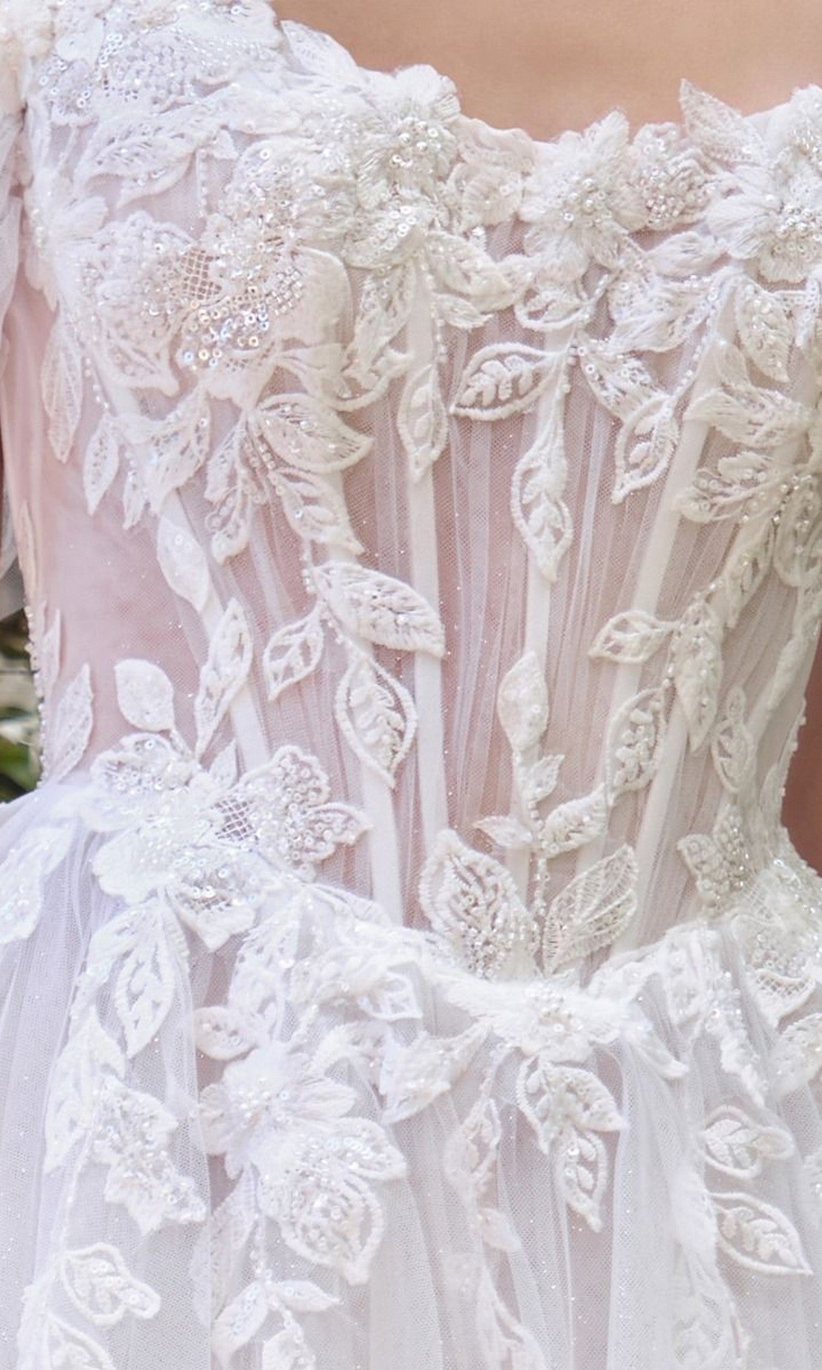 Close-up of the Andrea and Leo WL089 long wedding dress featuring off-the-shoulder design, floral lace appliques, beading, and sheer detailing on the bodice and upper skirt.