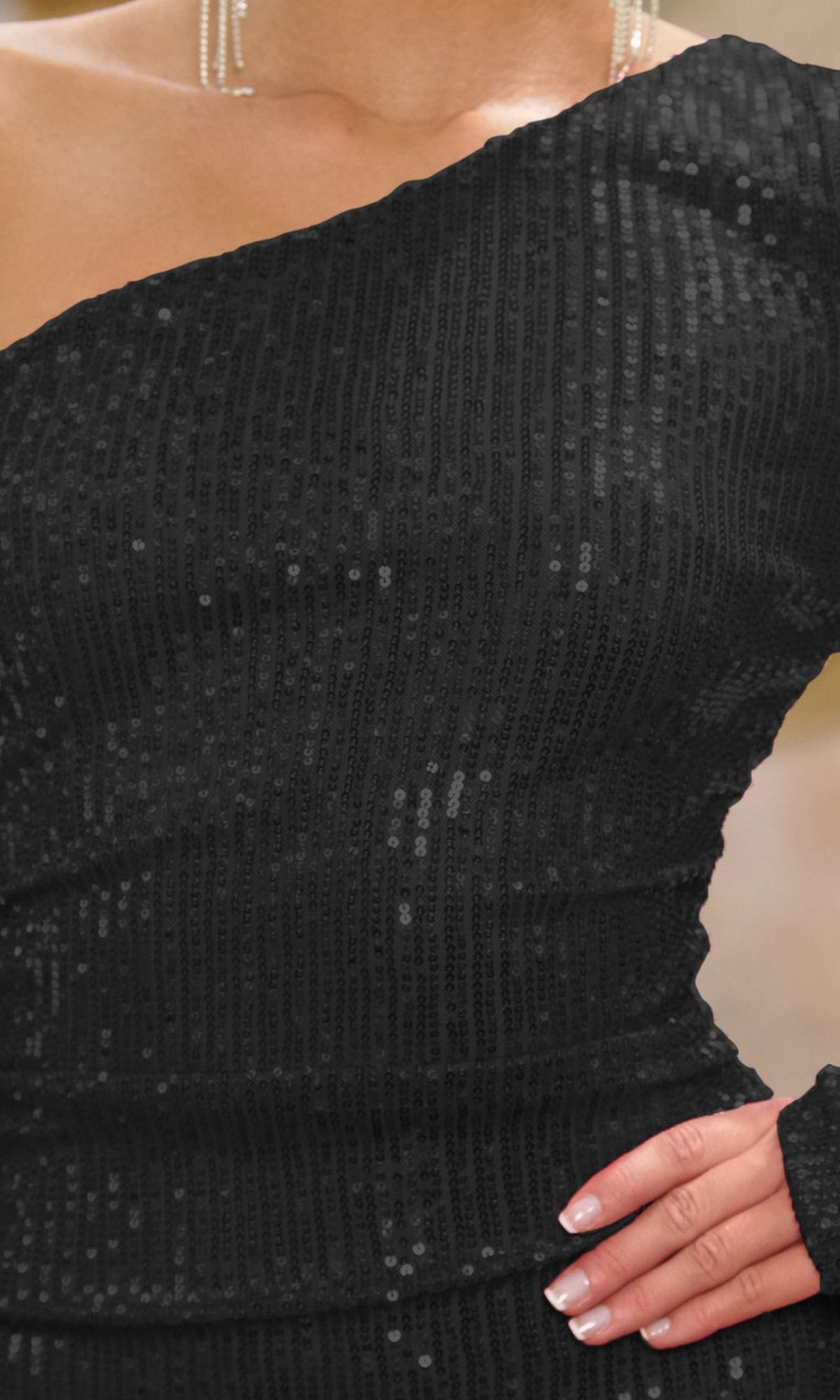 A person wearing the affordable Zena One-Sleeve Short Sequin Homecoming Dress in black, paired with a necklace, displays manicured nails and rests their hand on their hip.