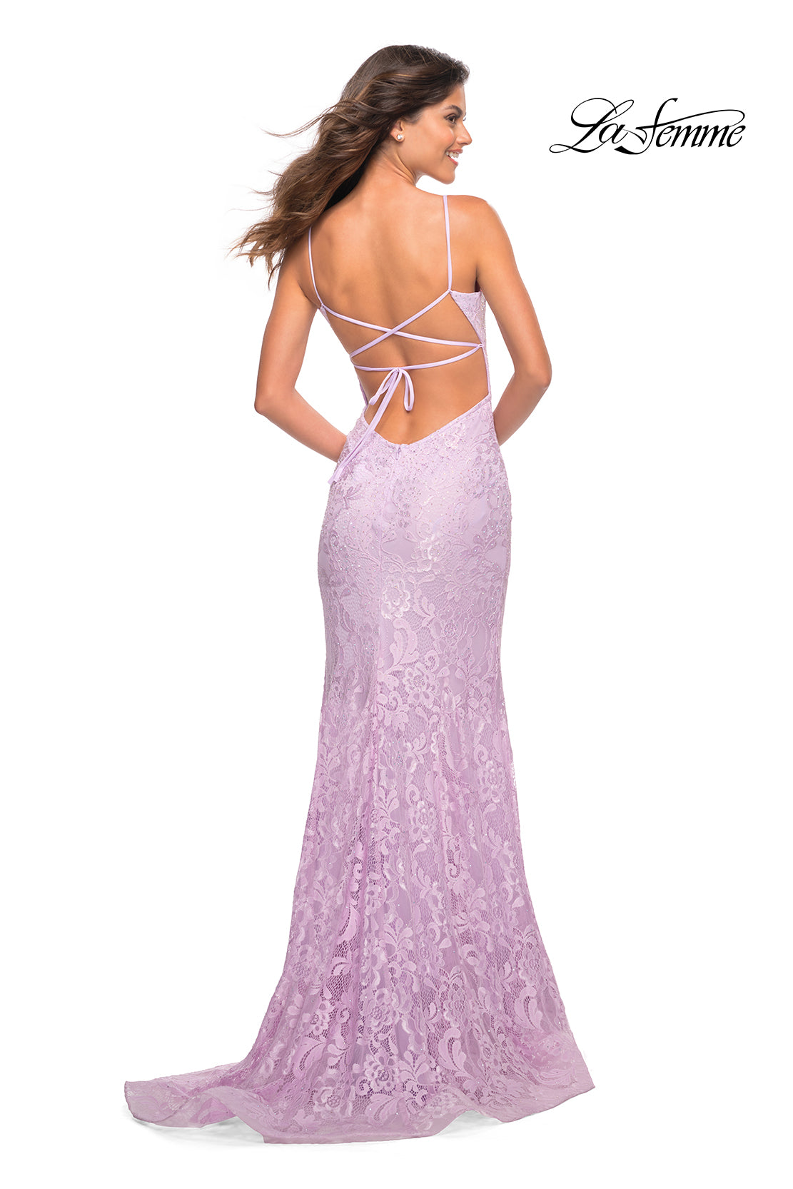 Woman wearing a lavender La Femme Stretch Lace Long Strappy-Back Prom Dress featuring a v-neckline and thin crisscross straps, standing and looking to the side.