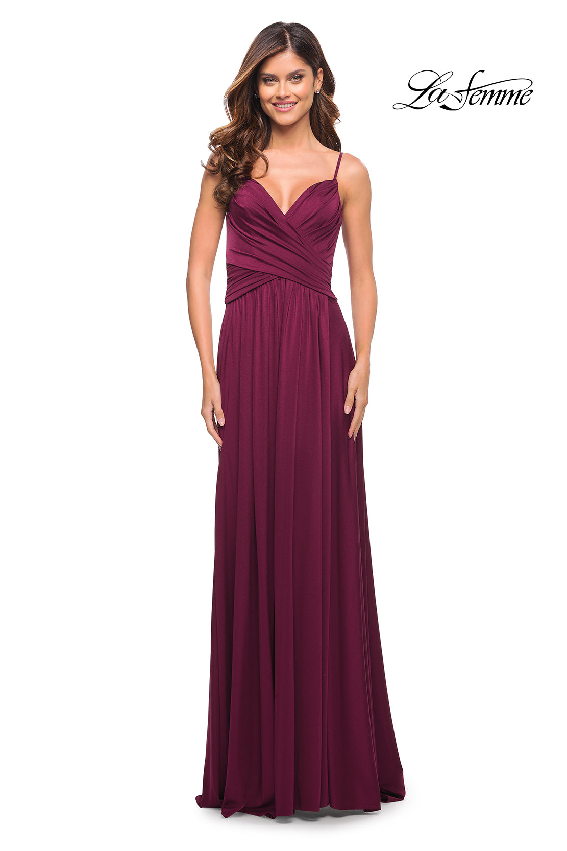 A woman wearing a sleeveless, floor-length La Femme Simple Elegant Long Formal Prom Dress in Dark Berry with a ruched bodice smiles against a white background. The