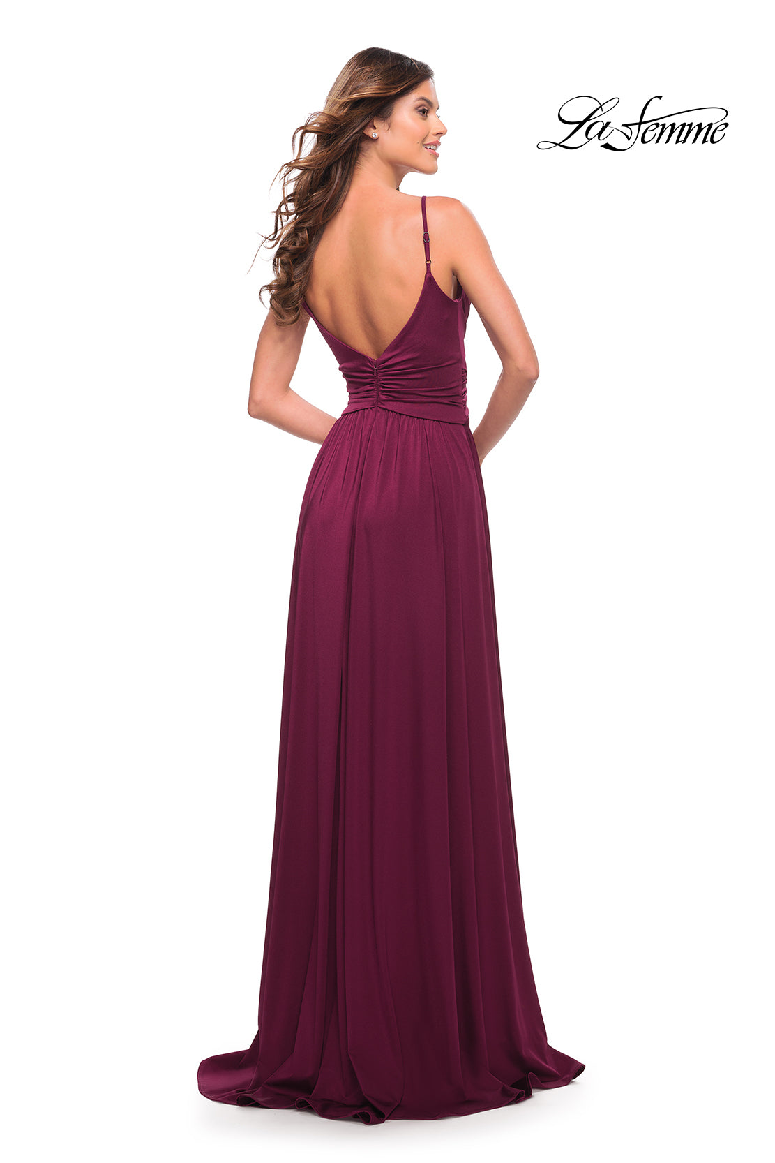 A woman wearing a sleeveless, floor-length burgundy La Femme Simple Elegant Long Formal Prom Dress with a deep V-back stands facing away from the camera. The La Femme logo appears in the top right corner.