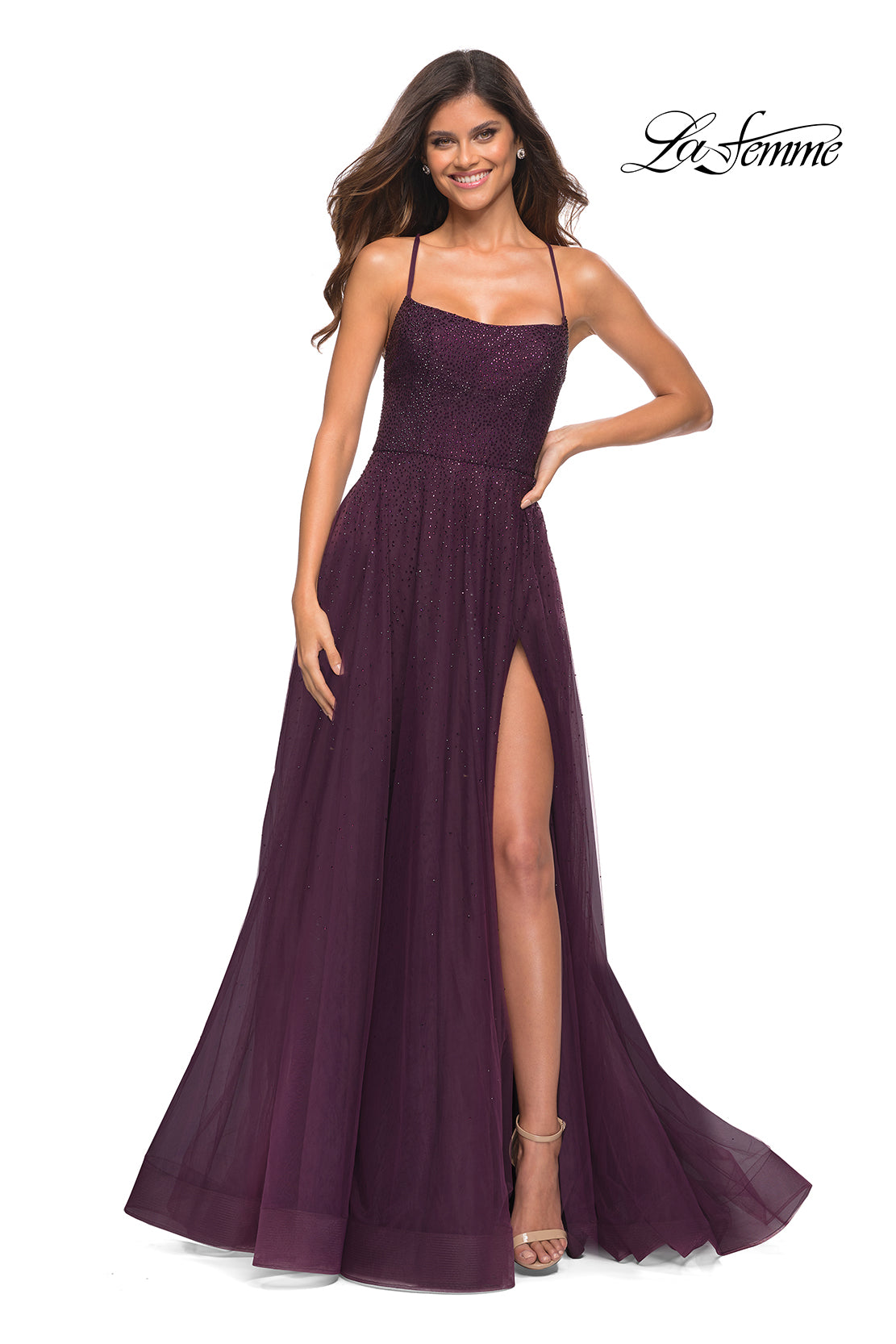 A woman smiles in a sleeveless, floor-length Corset-Back Long La Femme A-Line Prom Dress with a beaded bodice, thigh-high slit, and spaghetti straps. The