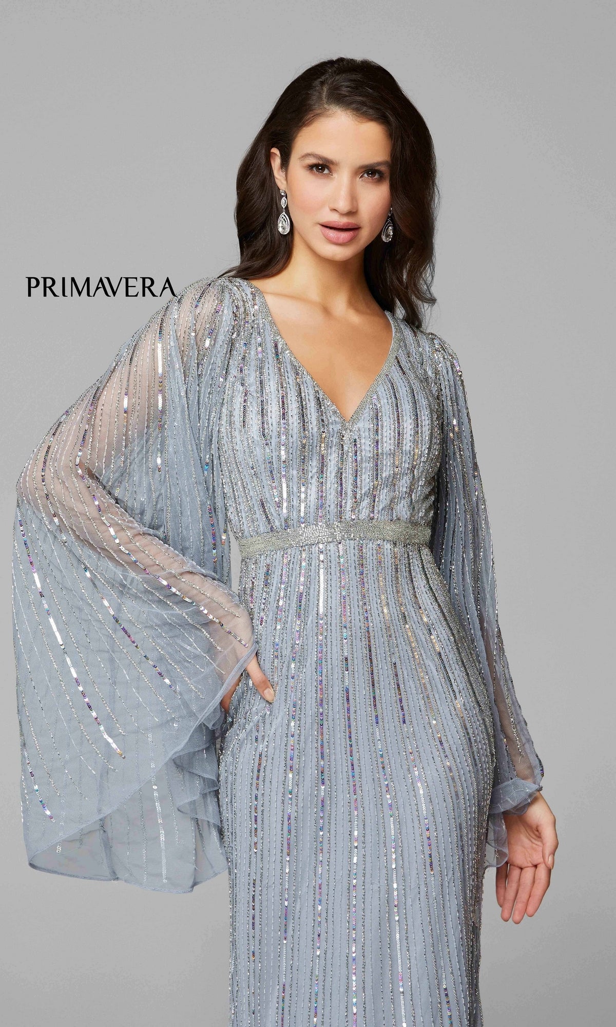 A woman poses before a gray backdrop with the