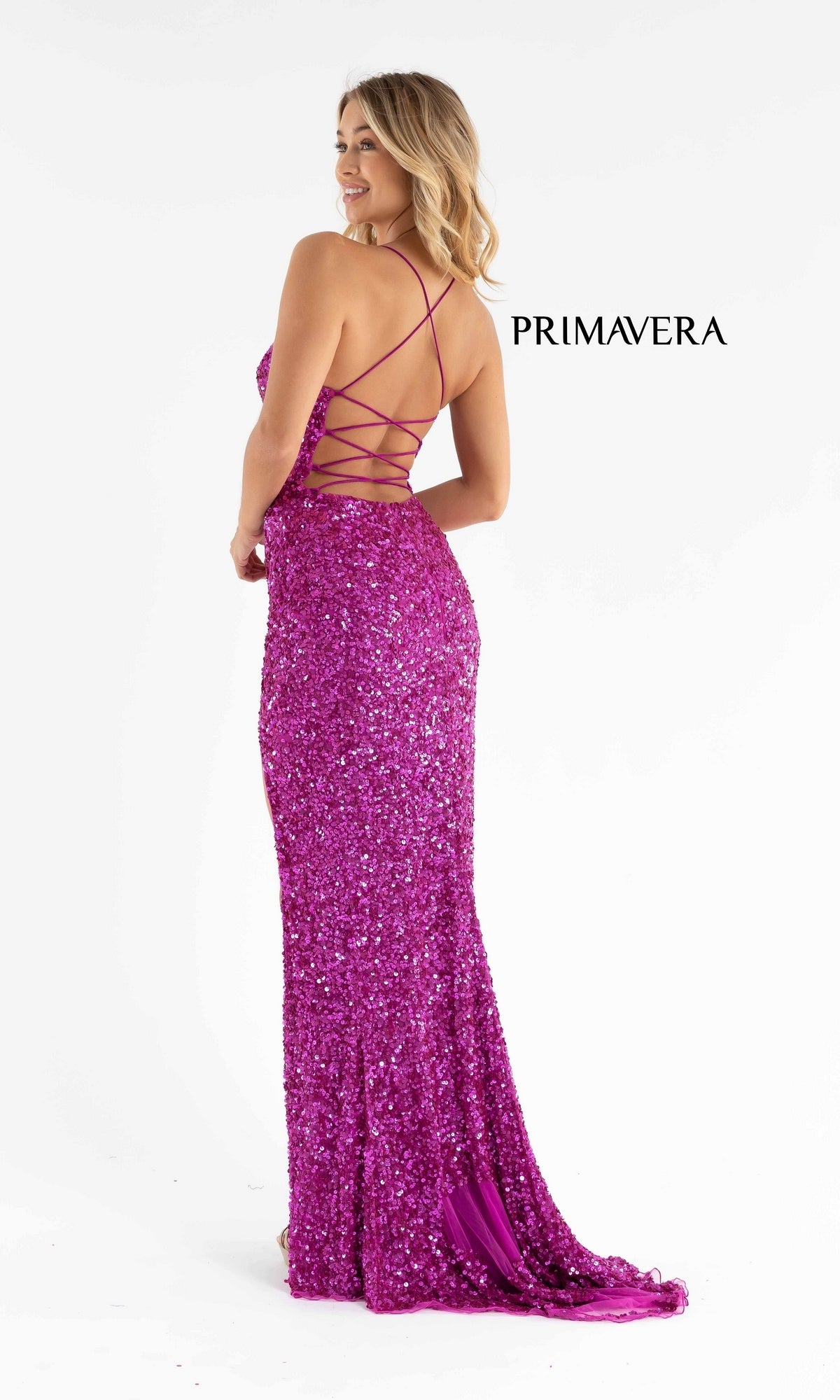 Woman wearing the Bright Wrap-Style Long Sequin Prom Dress 3791B, which features a sparkly purple design and crisscross straps on the back, standing and looking over her shoulder.