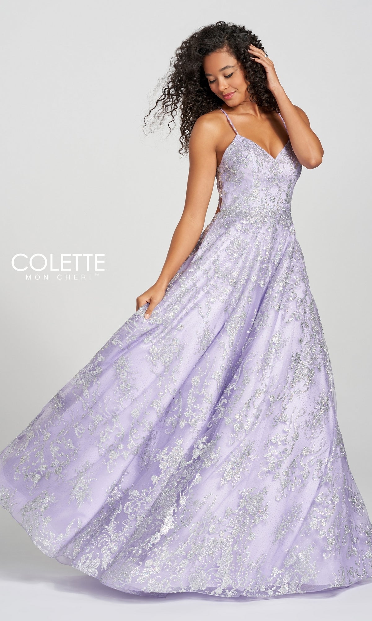 A woman poses in the Violet Purple Prom Dress with Silver Glitter Print, featuring thin straps and a flared skirt, against a plain background.