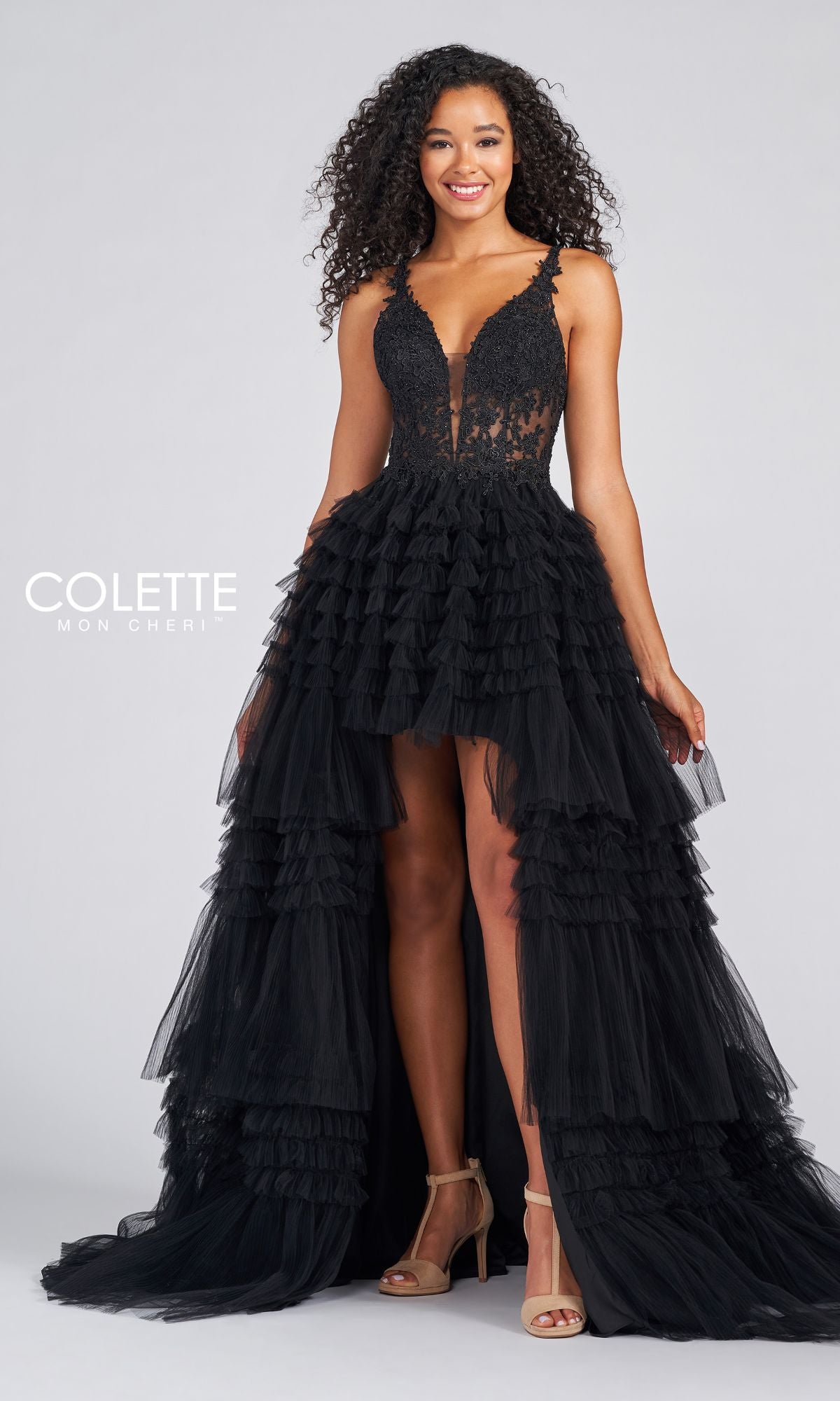 A woman stands smiling against a plain background, wearing the High-Low Tiered-Tulle Prom Dress CL12281 featuring a black sleeveless design, ruffled tulle skirt, and lace bodice.