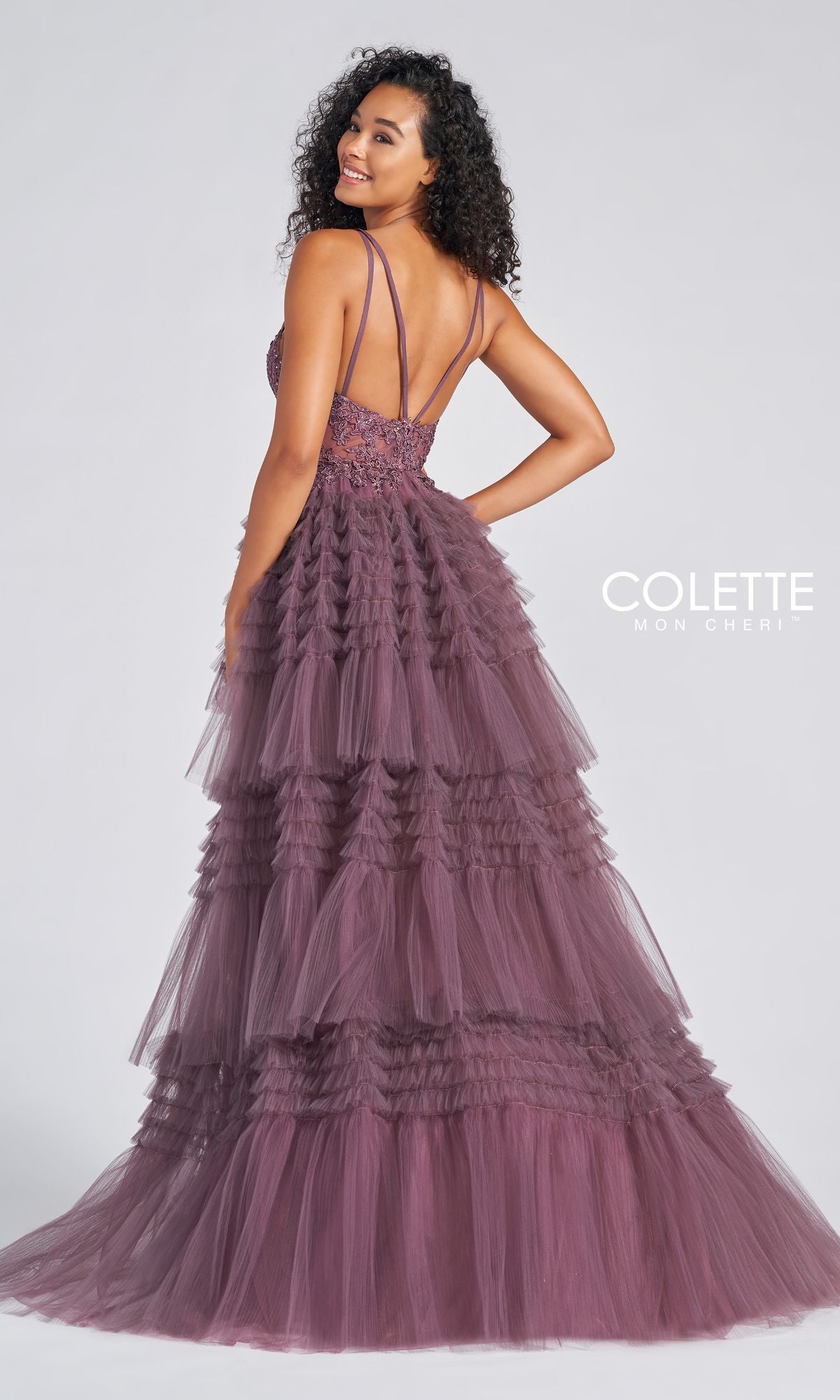 A woman smiles over her shoulder in the High-Low Tiered-Tulle Prom Dress CL12281, a mauve design with thin straps and tiered tulle layers. The