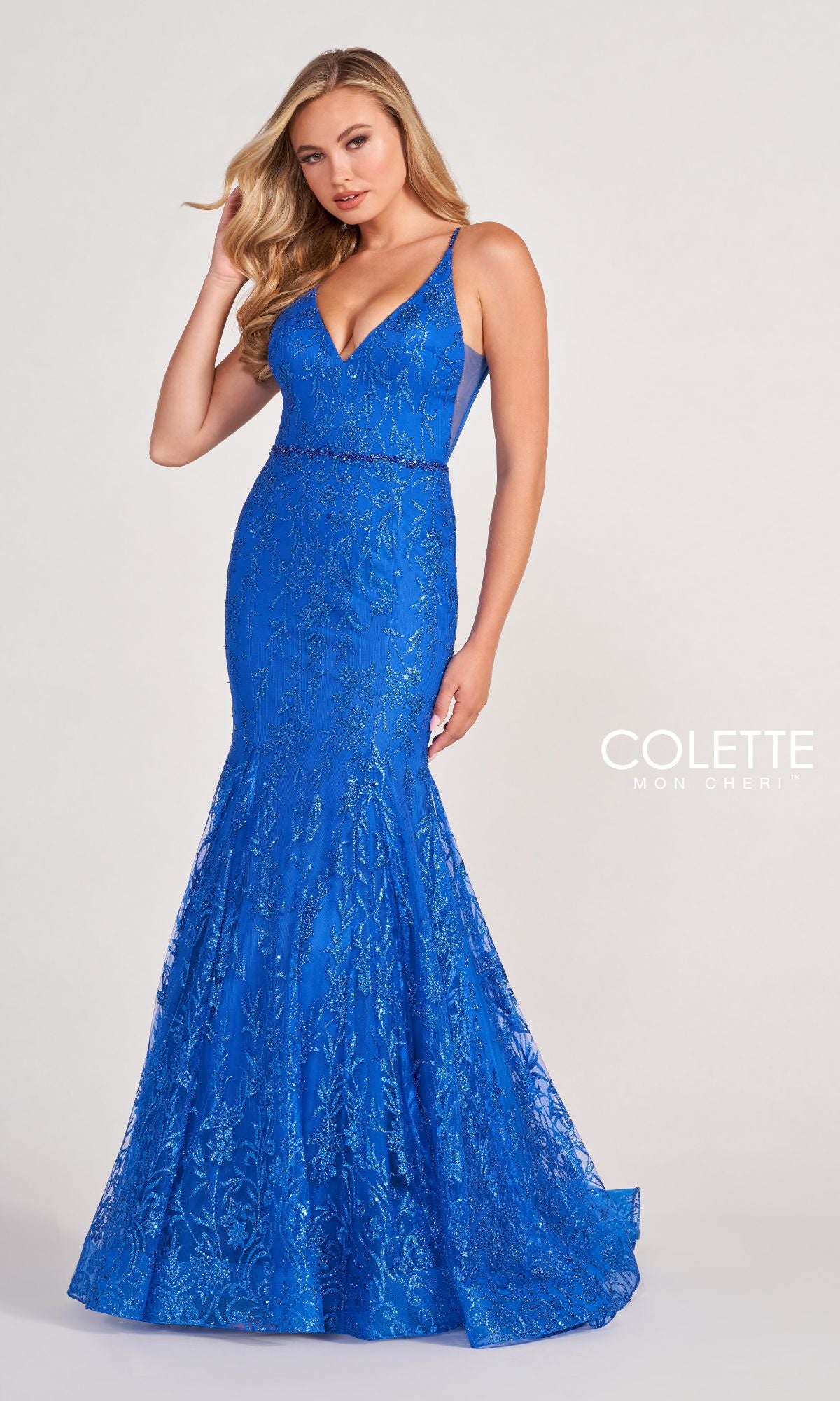 A woman wears the Colette CL2021 Long Mermaid Glitter Prom Dress, a sleeveless, floor-length royal blue gown with sequin detailing, standing against a plain light background.