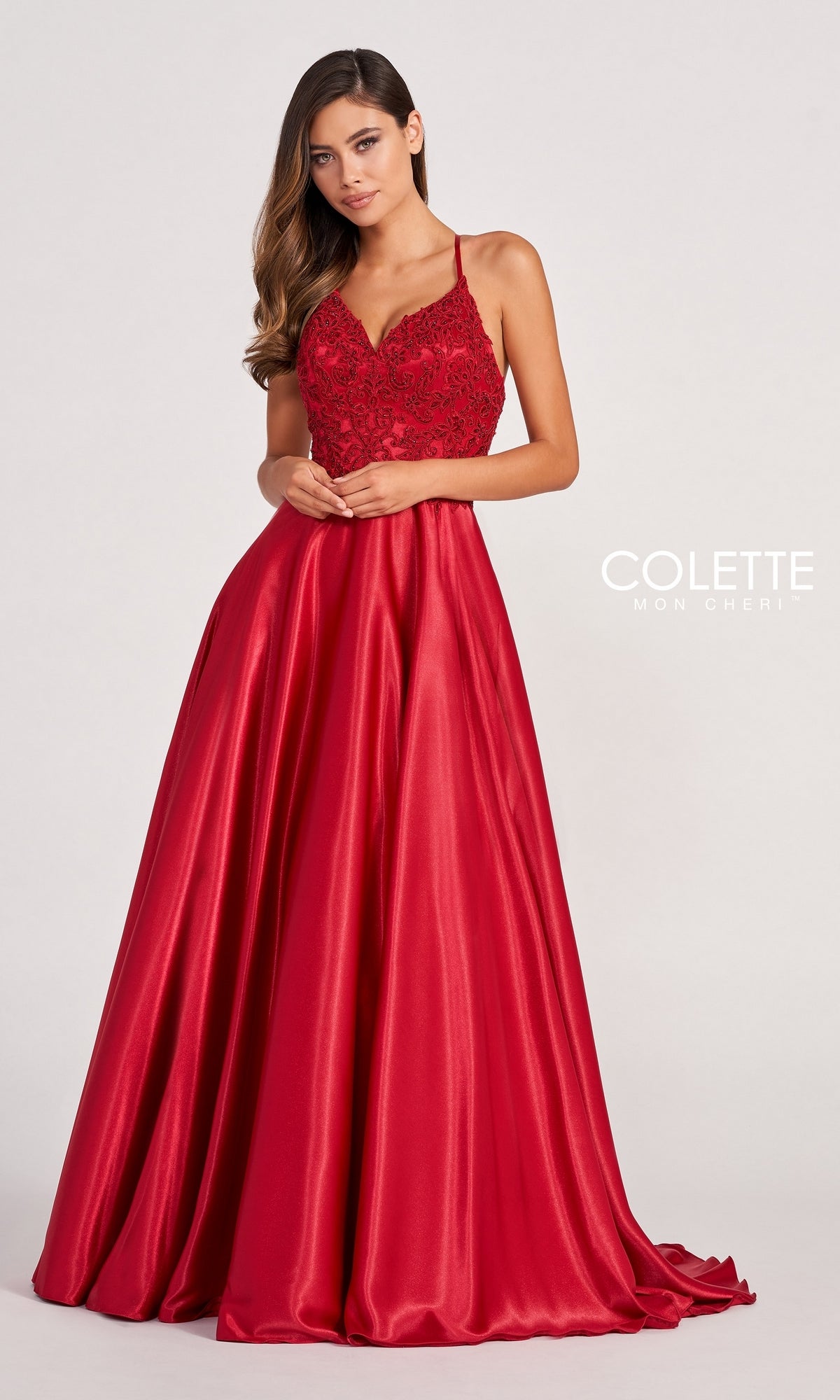 A woman wears the Colette by Daphne Satin Prom Ball Gown CL2033, featuring a sleeveless fitted lace bodice and an A-line, floor-length skirt, standing against a plain light background.