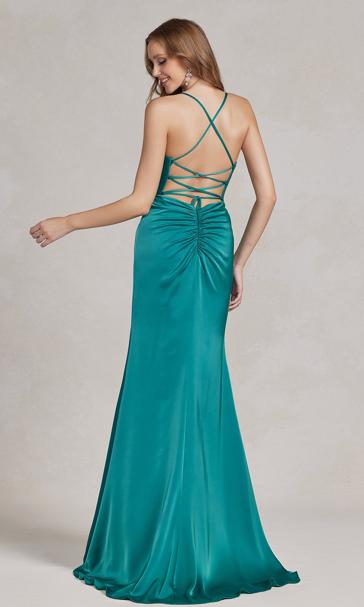 A woman wears the Cowl-Neck Classic Prom Dress with Side Slit, featuring teal satin fabric, ruched details, an open back with crisscross straps—an elegant choice for formal events—posed against a neutral background.