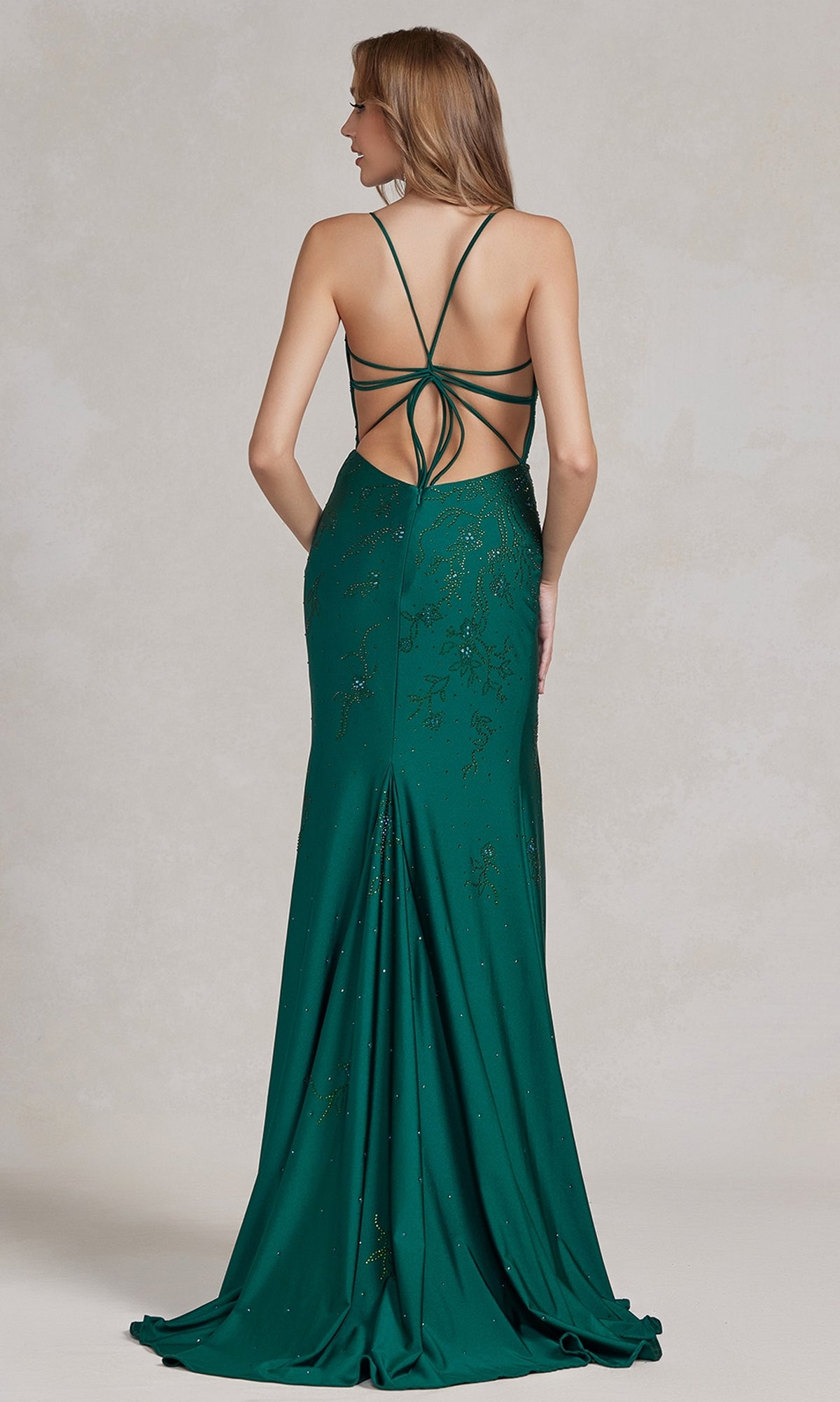 Woman in a green Backless Prom Dress with a floral beaded pattern and crisscross straps, floor-length with an open back, posed against a neutral background.
