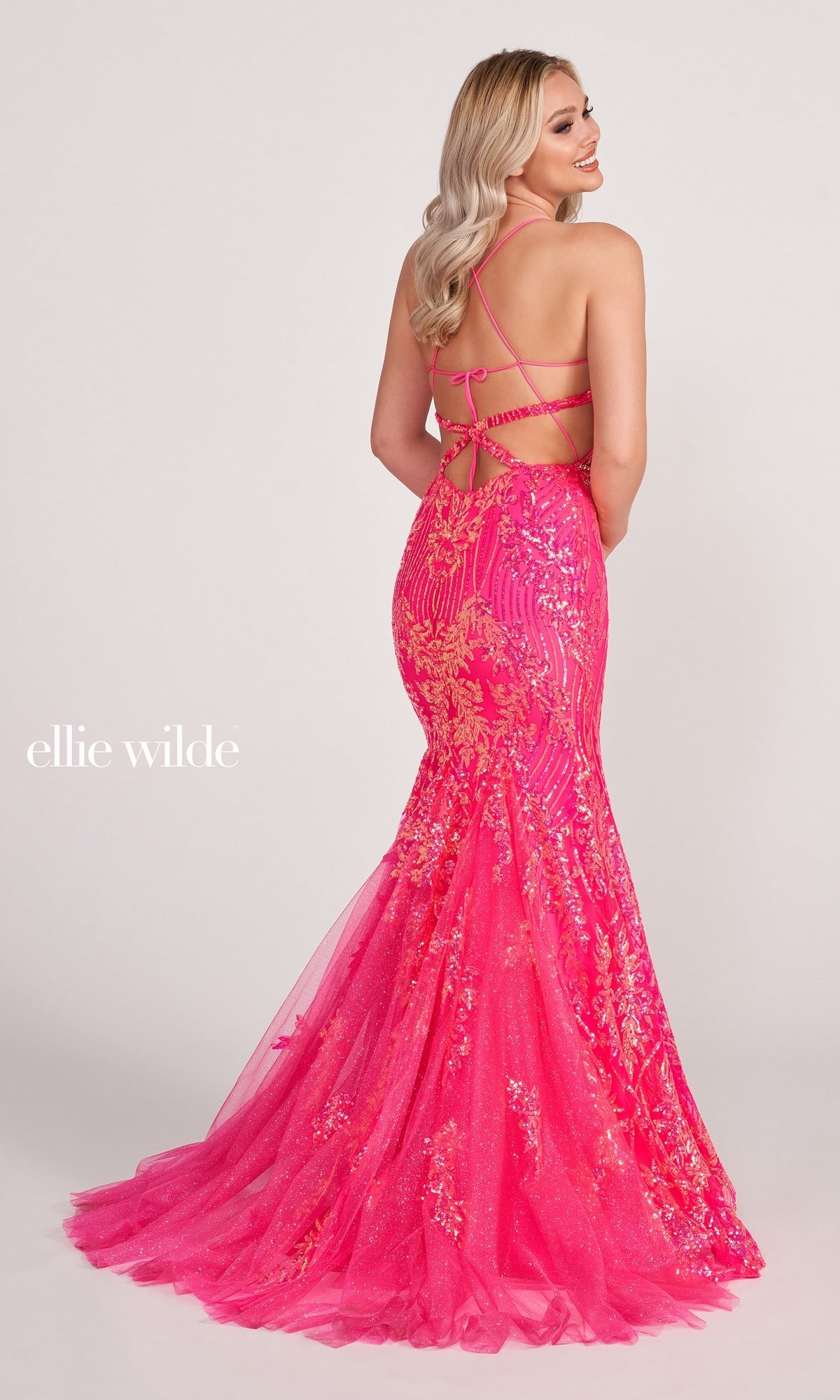 A woman showcases the strappy open-back design of the Sheer-Corset Long Sequin Mermaid Prom Dress, a bright pink, floor-length gown with gold sequin detailing and a dramatic mermaid silhouette.