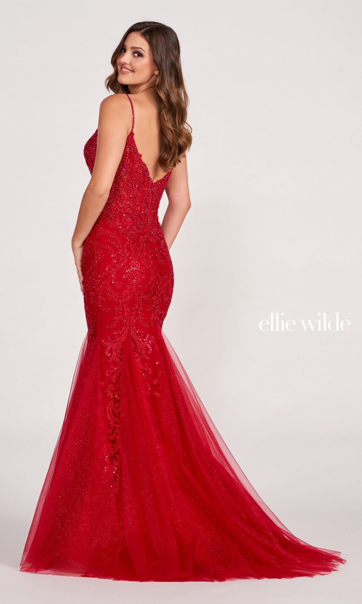 A woman models the Sheer-Bodice Embroidered Long Mermaid Prom Dress, a dazzling red gown with intricate beading, fitted mermaid silhouette, and low back, elegantly posed against a light background with the