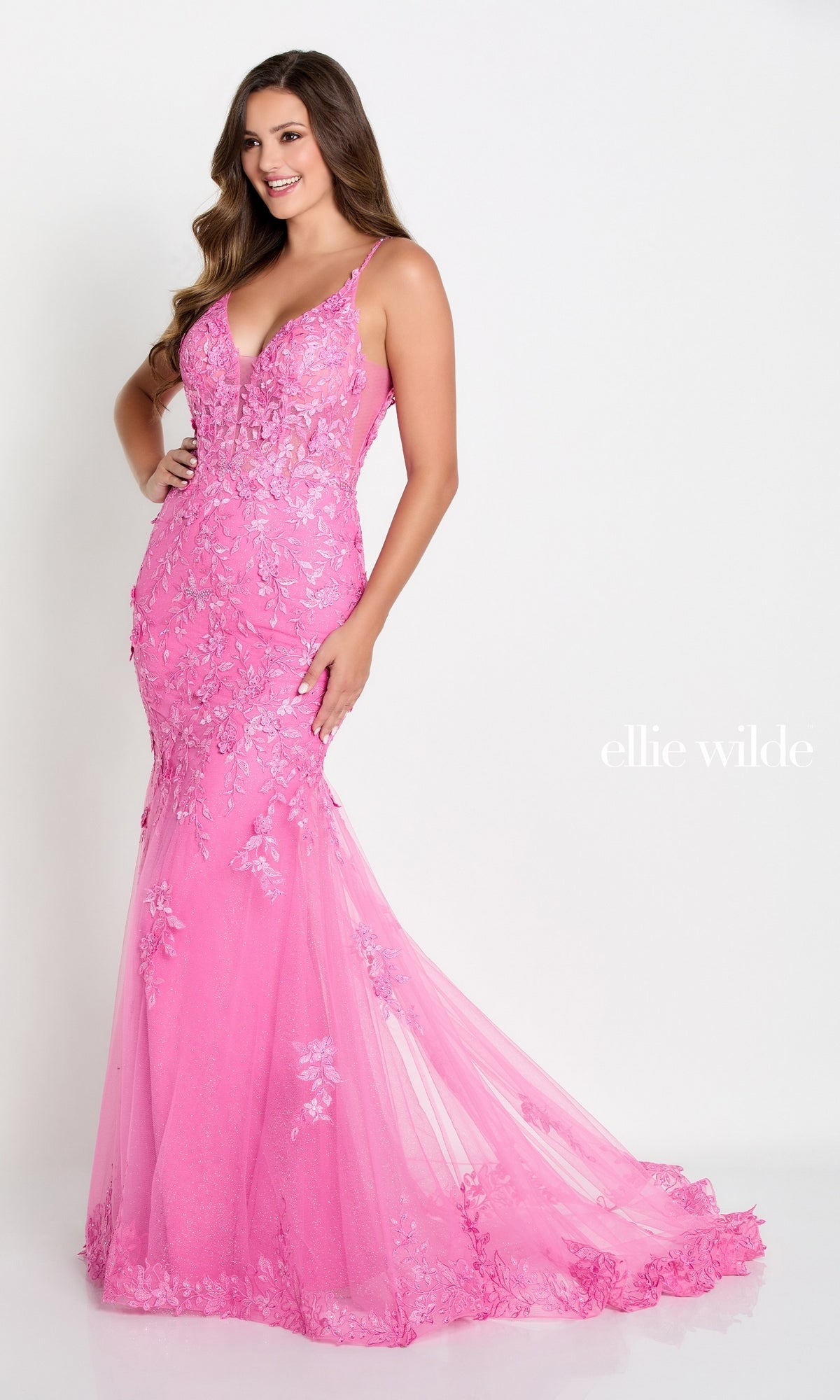 A woman poses in a Lace Embroidered Mermaid Gown With Sheer Bodice, featuring a sleeveless design, floral lace details, a fitted sheer corset bodice, and a floor-length mermaid skirt against a white background.