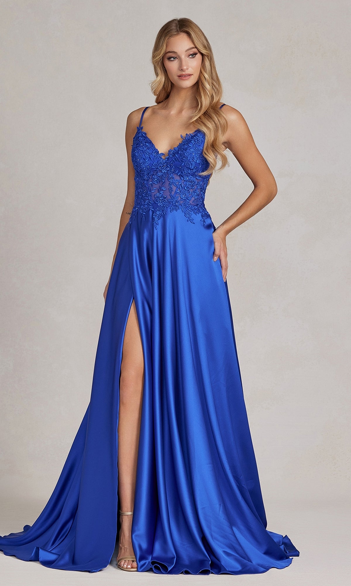 A woman wearing the Faux-Wrap A-Line Long Prom Dress with Corset, featuring a royal blue hue, beaded-lace bodice, spaghetti straps, and high front slit, stands against a neutral background.