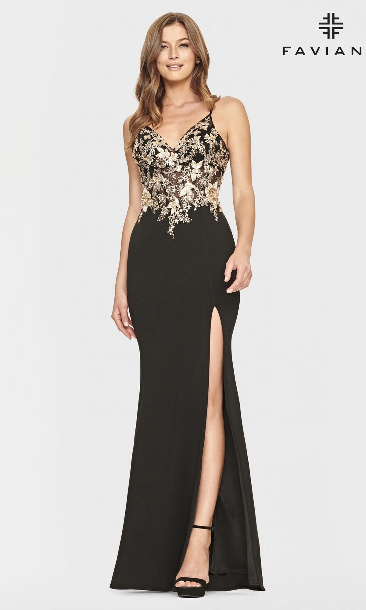 A woman in the Black and Gold Faviana Long Prom Dress S10853, featuring gold floral bodice appliques, a thigh-high slit, and black high heels, stands against a plain white background.
