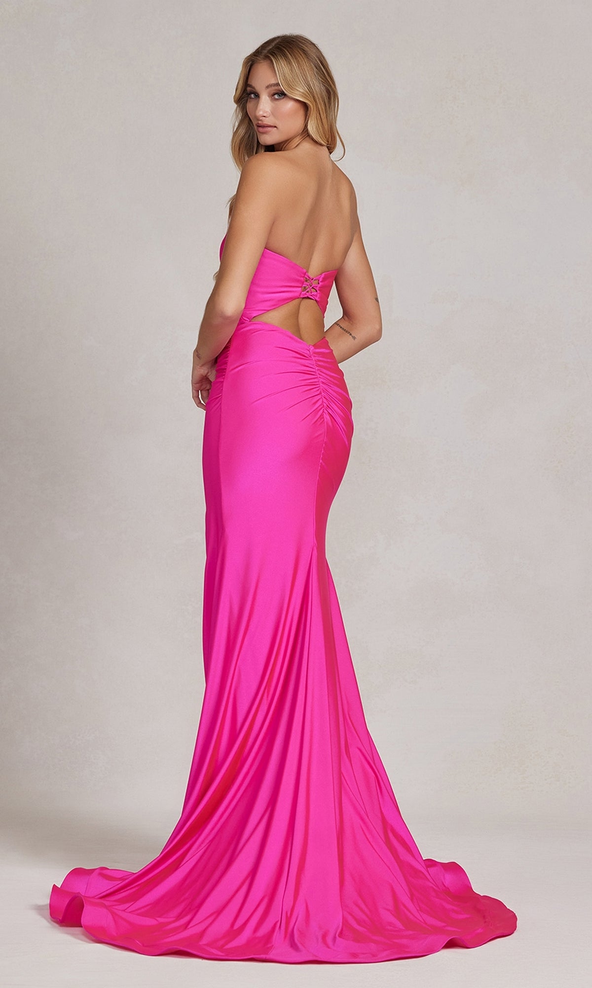 Woman wearing the Tight Long Sweetheart Strapless Formal Dress T1139 in hot pink, featuring a ruched back detail and long train, standing and looking over her shoulder.