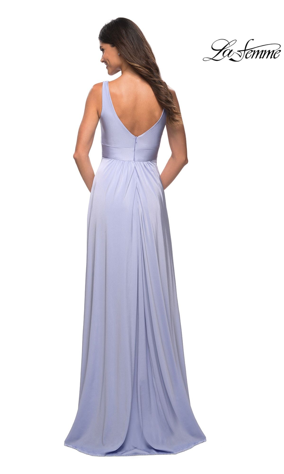 A woman stands facing away, wearing a sleeveless lavender La Femme Simple Long A-Line Formal Dress featuring a floor-length pleated skirt and deep V-back.