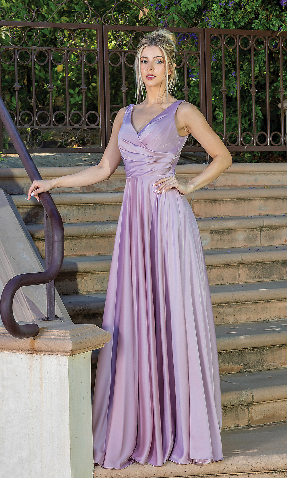 A woman wears the Wrap-Bodice Long A-Line Prom Dress with Corset, a sleeveless, light purple evening gown under $200, standing on outdoor steps with one hand on a railing and greenery behind her.