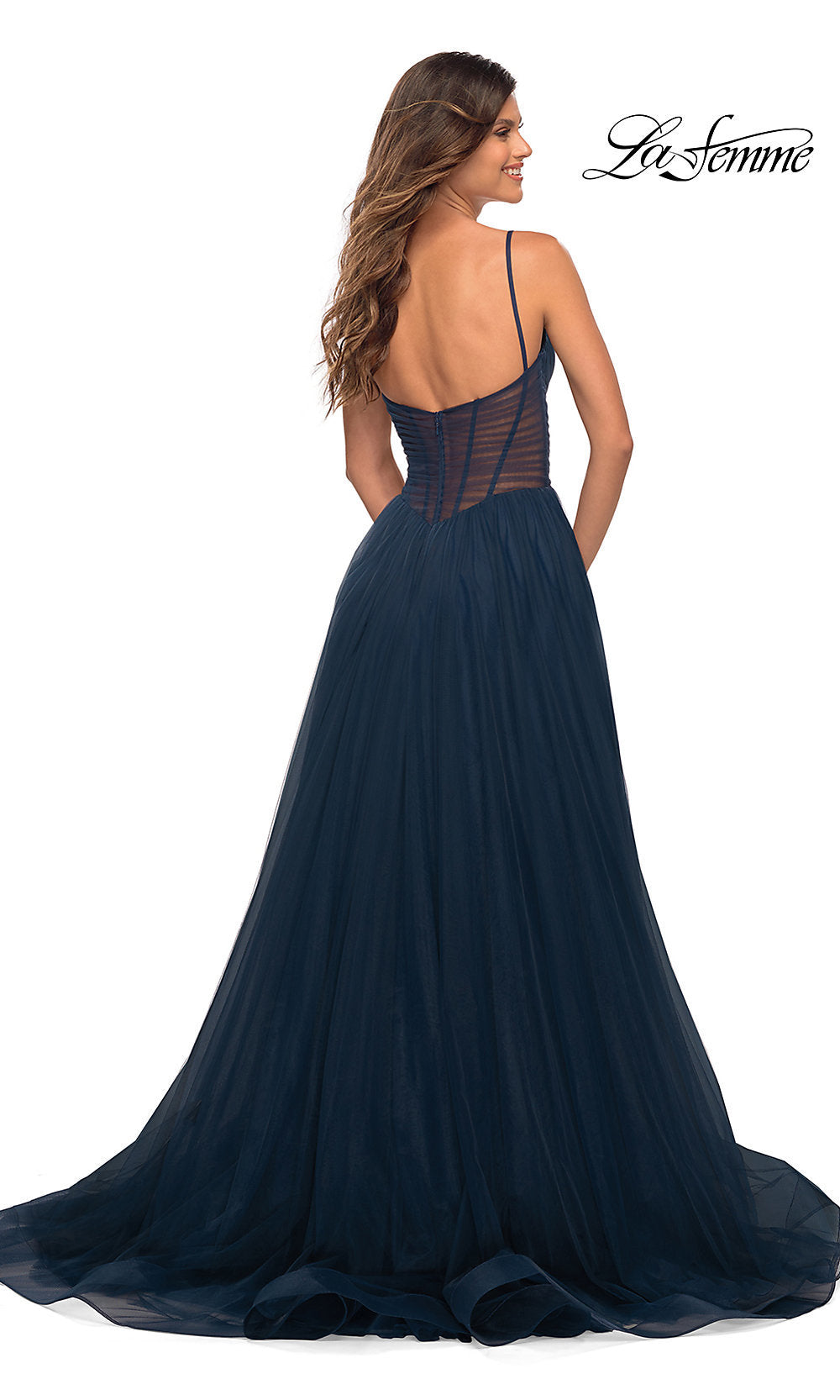 A woman is shown from the back wearing the Long La Femme Prom Dress with Sheer Corset Waist in navy blue tulle, featuring thin straps and a floor-length skirt. The La Femme logo appears in the top right corner.