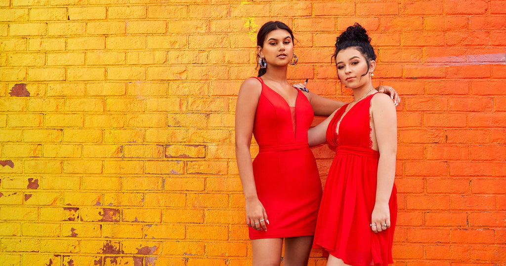 Two teen girls, one in a short fitted red dress and one in a short a-line red dress.