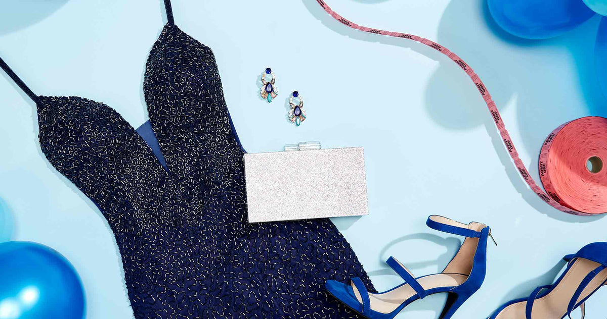Close up of a navy blue beaded prom dress, matching earrings, coordinating heels, and a silver prom clutch.