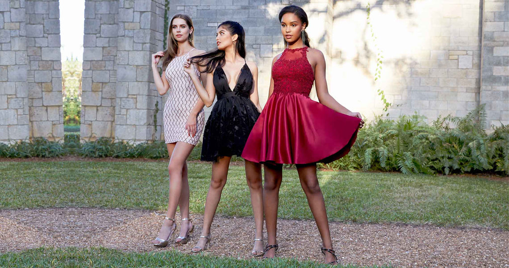Three teen girls wearing different homecoming dress styles on a rustic garden walkway.