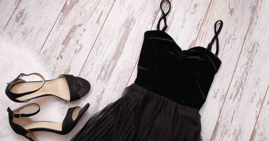 Close up of a black prom dress next to a pair of matching black heels.