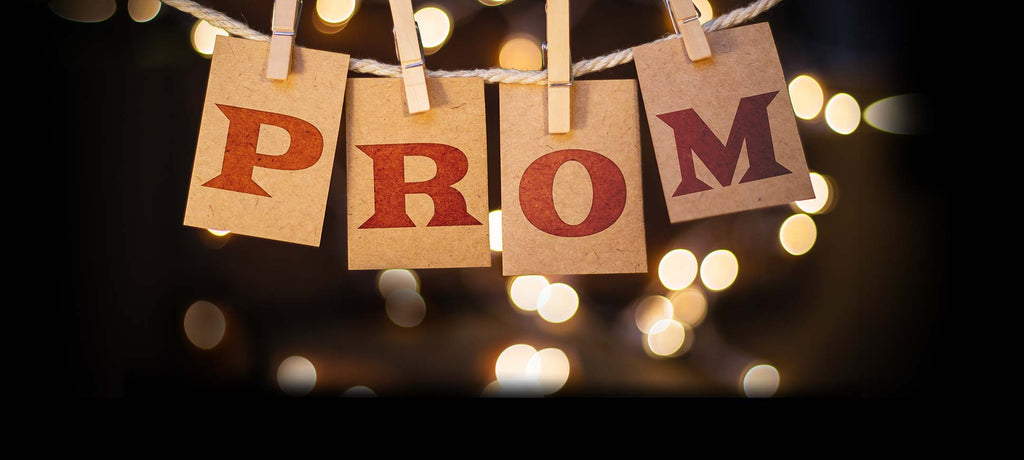 Letter cards that spell out "prom" and are held up on rope with clothespins.