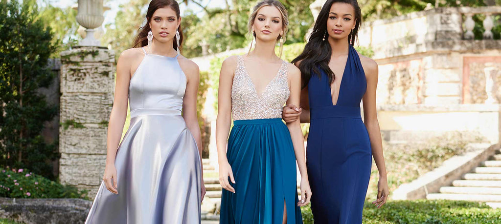 Three teens wearing prom dresses made from various fabrics that fit their figures differently.
