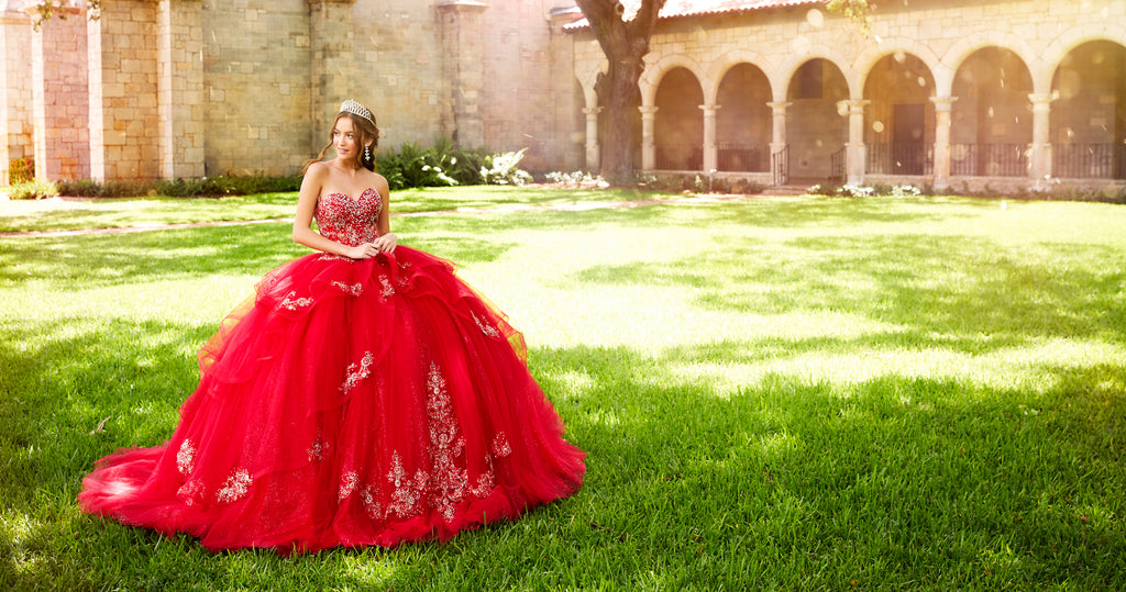 Teen girl wearing a strapless red quince ball gown with tiers and sparkling embellishments.