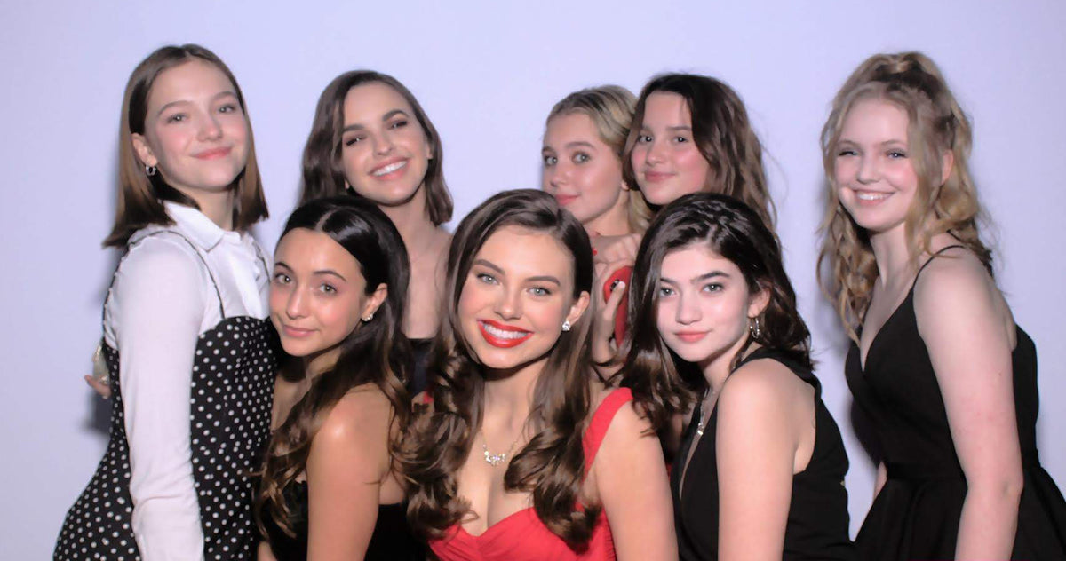 A group of teen girls in homecoming dresses smiling for a group picture.