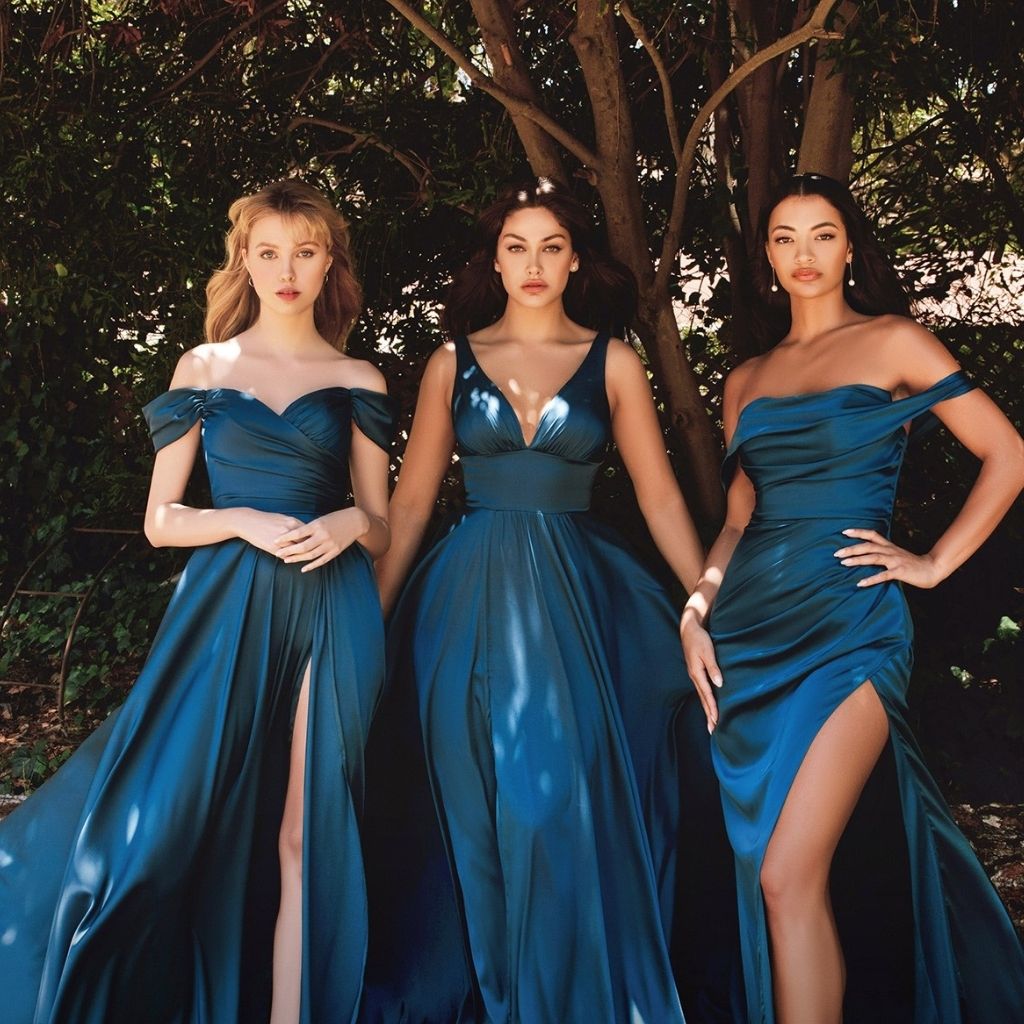 In navy blue formal dresses, three bridesmaids coordinate with an off-shoulder style, a ball gown, and a fitted ruched dress.