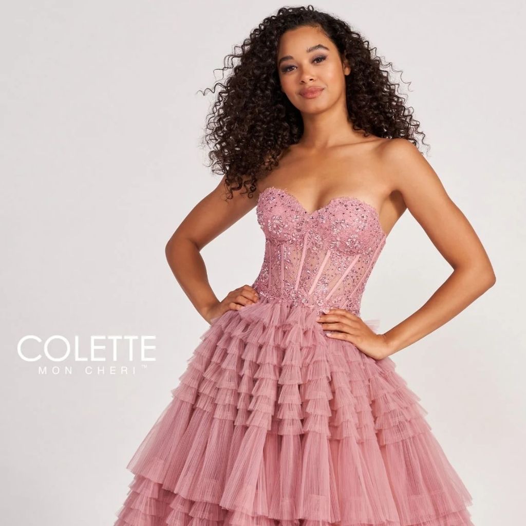 Close up of a teen girl wearing a strapless corset Colette by Daphne designer prom ball gown with a tiered skirt.