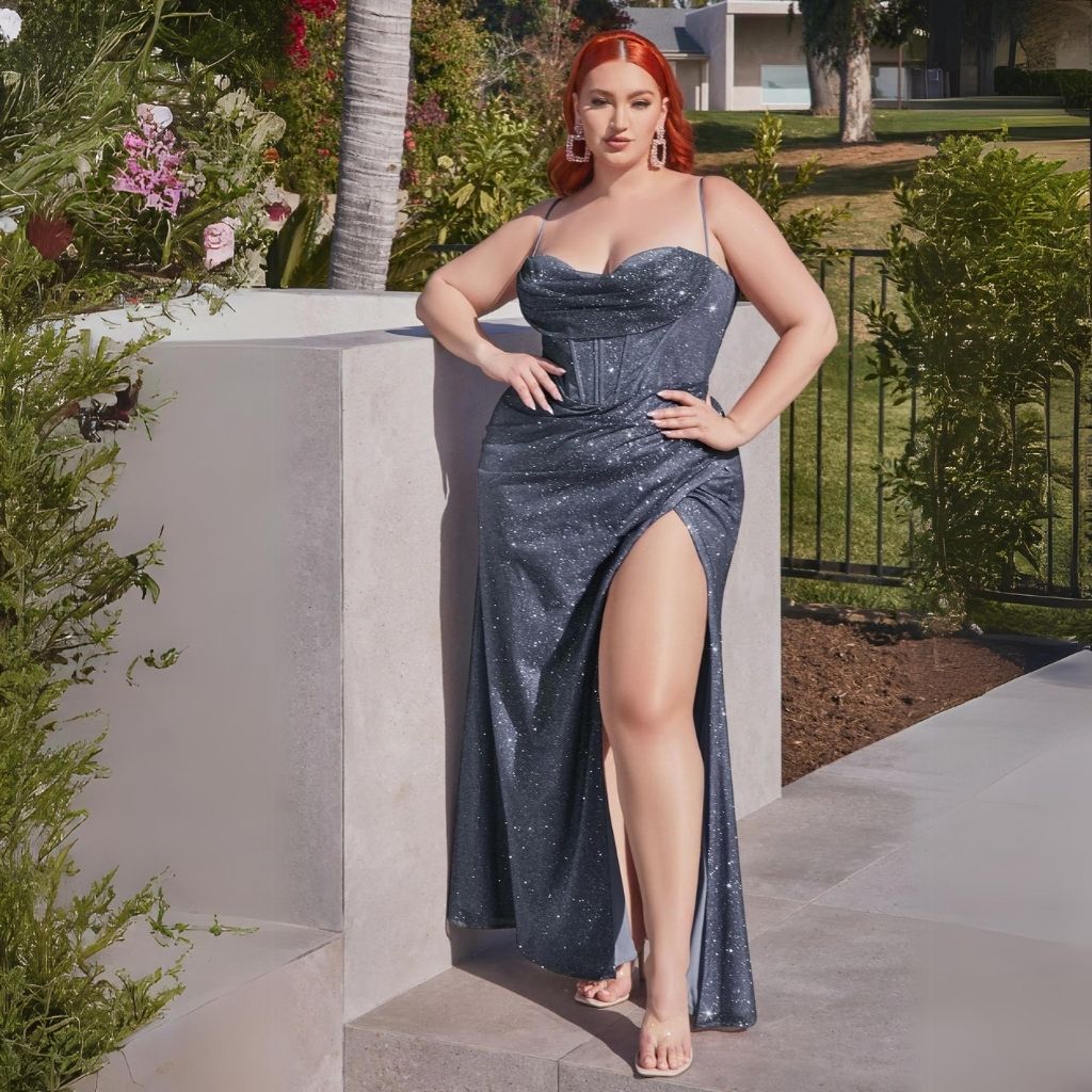 In a plus-size silver sequin prom dress, a teen girl leans against a stone wall next to a garden.