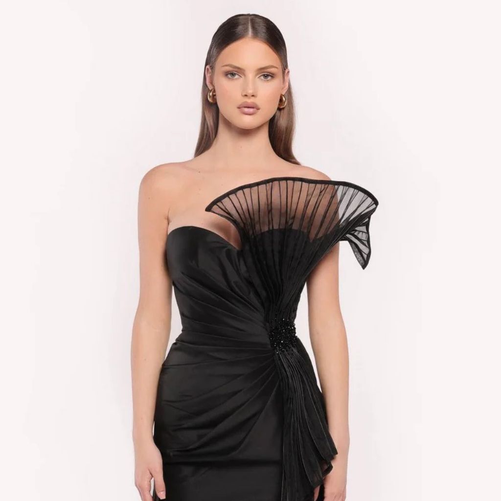 Woman modeling a black Tarik Ediz evening gown in front of a white background.