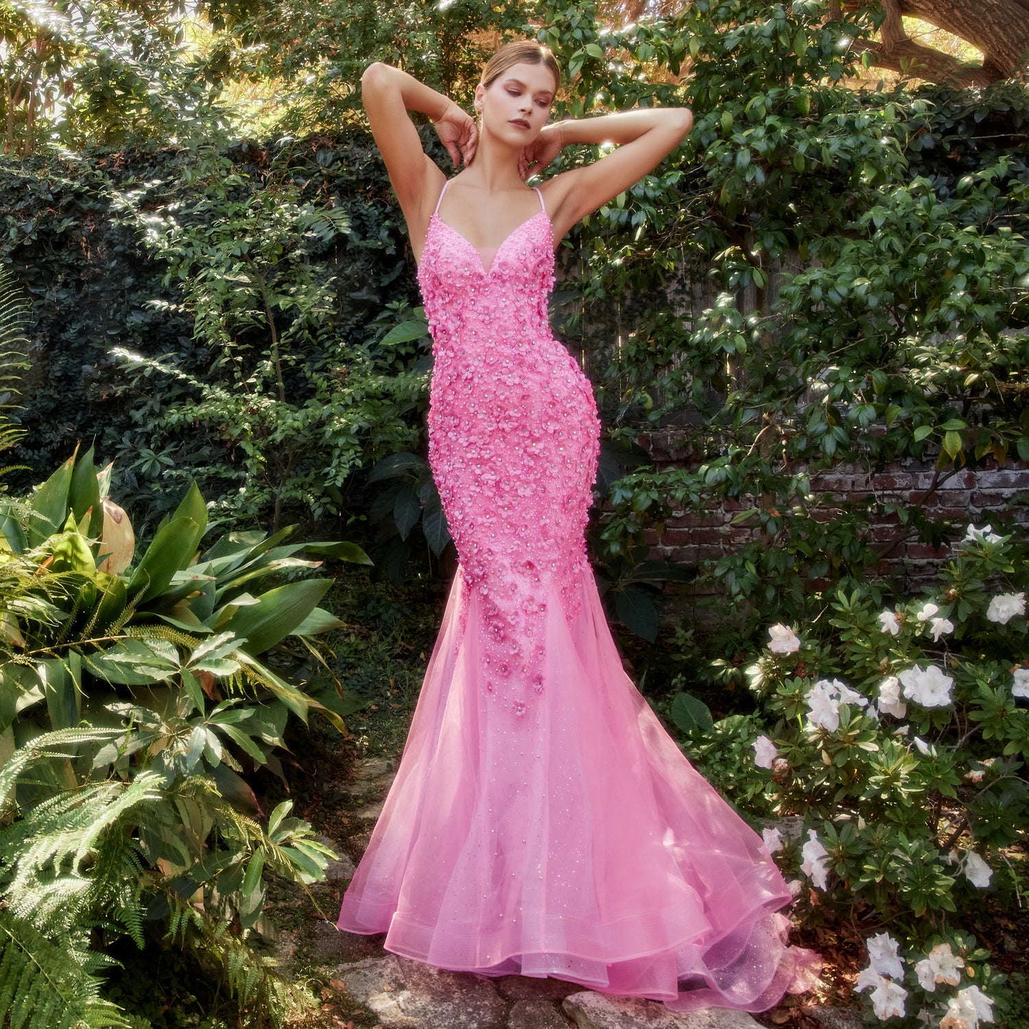 Image of woman standing outside in a garden wearing a light pink prom dress.