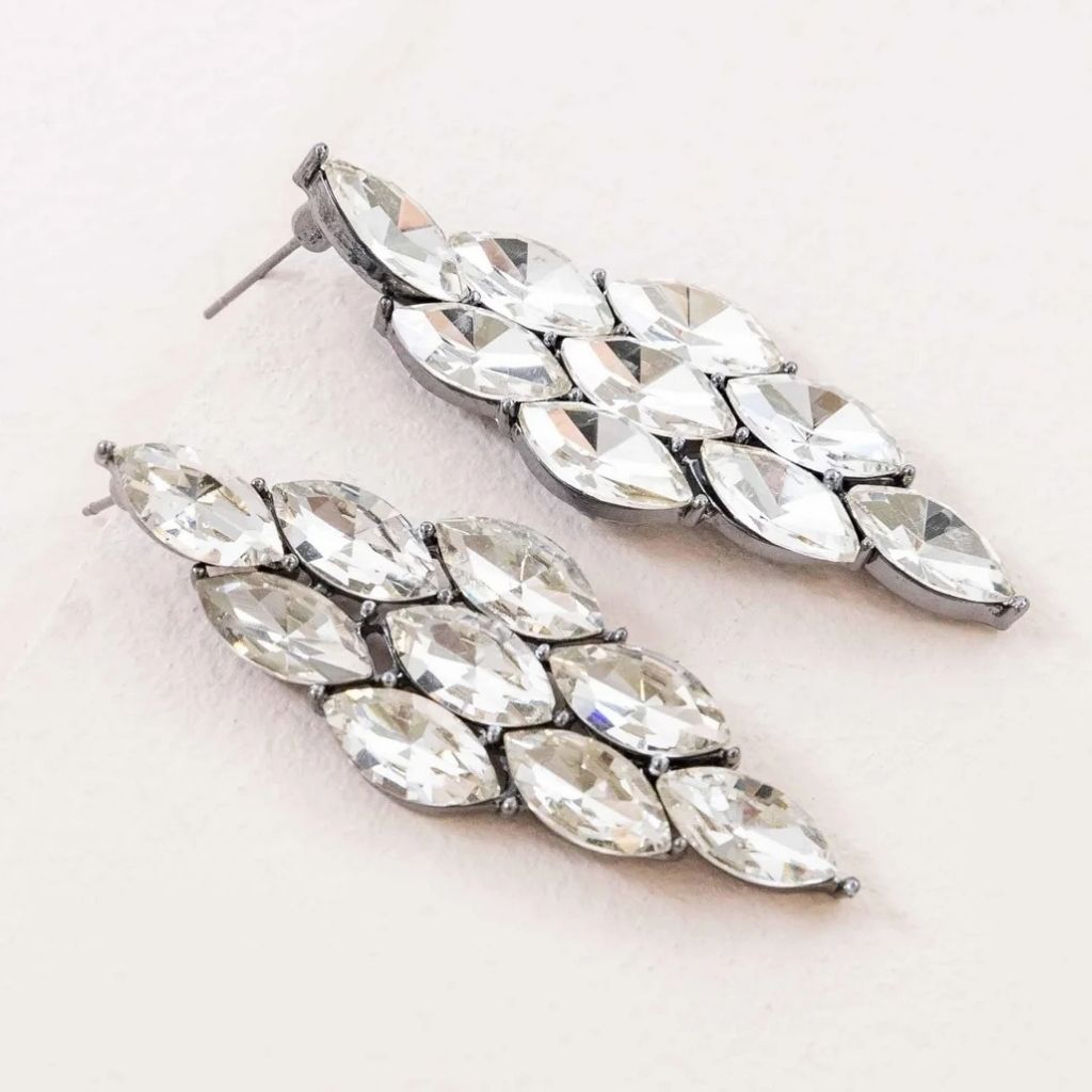 Close up of sparkling silver formal prom earrings set with several clear gemstones in a diamond shape.