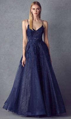 A woman wears the Embroidered Glitter-Tulle Long Prom Ball Gown 251, a sleeveless deep blue dress with a fitted bodice, flared skirt, lace, and glitter details, standing against a plain gray background.
