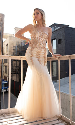 A woman wearing the Sheer-Corset Strapless Mermaid Prom Dress 774, with a jeweled corset bodice and gold embellishments, stands on a balcony gazing sideways, urban buildings in the background.