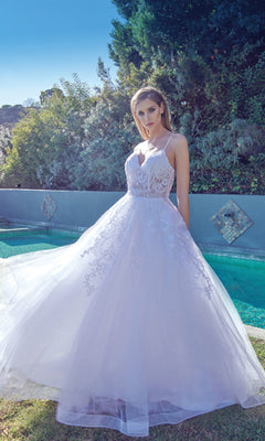 A woman in the Embroidered Glitter-Tulle Long Prom Ball Gown 251 poses outdoors by a pool amid lush greenery and a tiled wall.