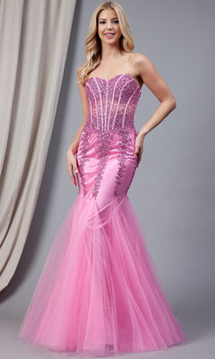 A woman wears the Sheer-Corset Strapless Mermaid Prom Dress 774, featuring a jeweled corset bodice, sequin accents, and a tulle skirt, standing before a gray backdrop with beige drapery.