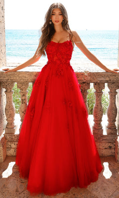 A woman in the Embroidered-Tulle Long A-Line Prom Ball Gown 7035, a bright red, floor-length dress with floral embroidery, stands on a stone balcony overlooking the ocean on a sunny day.
