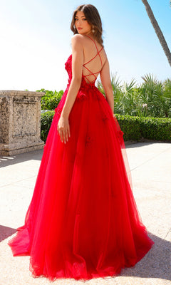 A woman stands outdoors amid lush greenery and palm trees, wearing the Embroidered-Tulle Long A-Line Prom Ball Gown 7035, featuring floral embroidery and crisscross back straps.