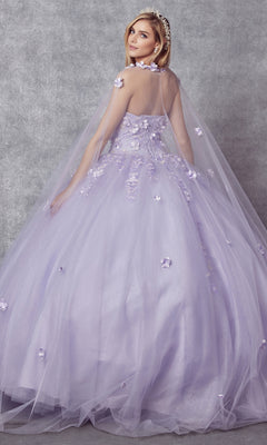A woman in the Juliet 1435 Strapless Ball Gown Quinceañera Dress, featuring floral appliqué and a sheer cape, poses against a gray textured backdrop.
