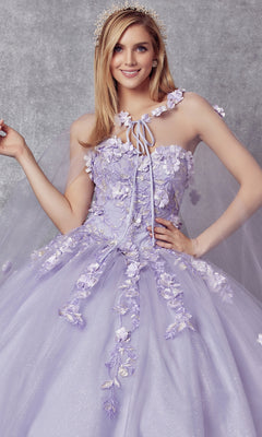 A woman wears the Juliet 1435 Strapless Ball Gown Quinceañera Dress in lavender, featuring 3D floral appliqués and a sheer cape, posed against a neutral background—an elegant quinceañera choice.