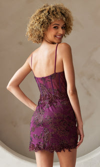 Smiling over her shoulder, a woman with curly hair wears the Asymmetrical-Hem Short Homecoming Dress 5059S—fitted, purple, beaded, and featuring thin straps.