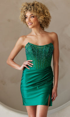 Woman wearing the Beaded-Bodice Strapless Short Hoco Dress 3021S, a fitted green dress with a beaded corset bodice and ruched satin skirt featuring a thigh-high slit.