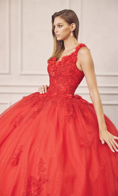 A woman stands against a light-colored, textured wall wearing the Juliet 1437R Red Ball Gown Quinceañera Dress, featuring floral lace and beaded embroidery.