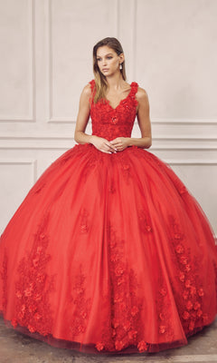 A woman wears the Juliet 1437R Red Ball Gown Quinceañera Dress, featuring a fitted bodice, beaded embroidery, floral details, and a full tulle skirt, standing before a neutral paneled wall.